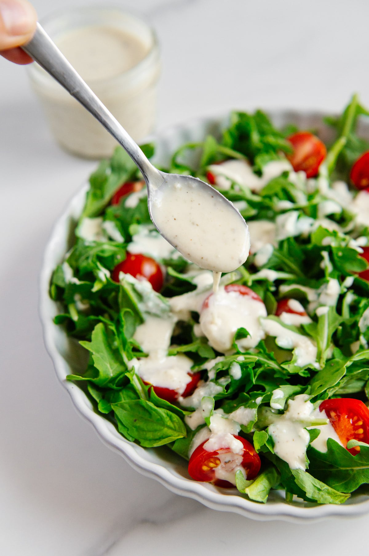 A spoonful of vegan Italian dressing above a dressed salad.