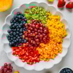 Finely chopped fresh fruit in a white bowl prior to being tossed together with a white background.