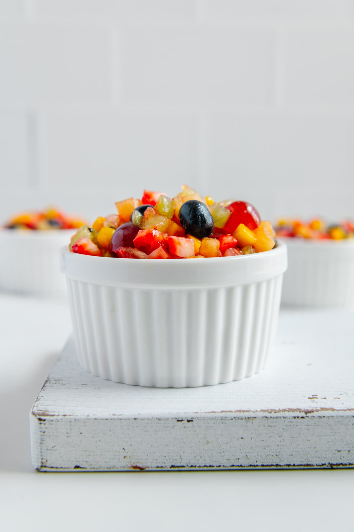 Nature's Skittles fruit salad in a white ramekin with a white background.