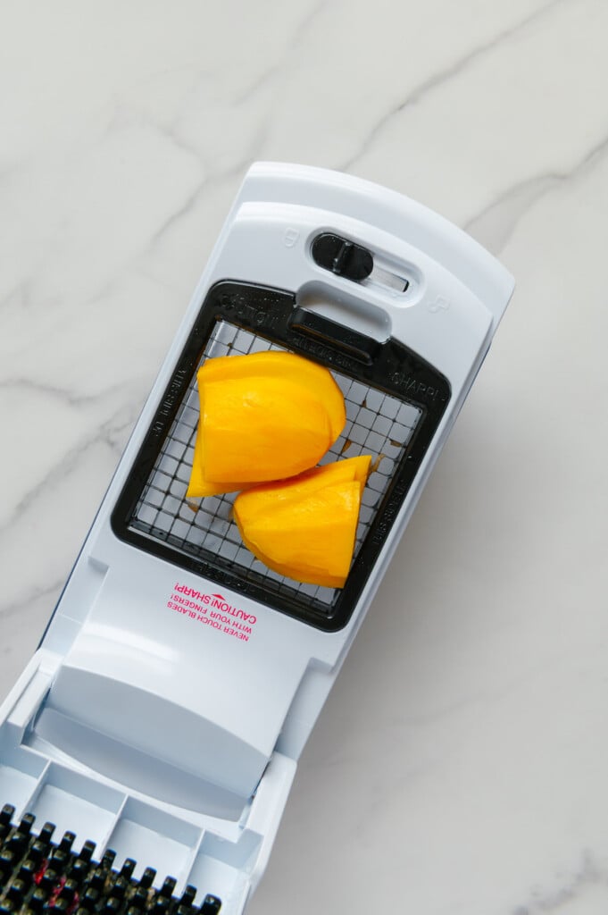Champagne mango slices in a veggie chopper prior to being chopped.
