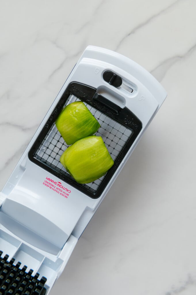 Two kiwi halves on a veggie chopper prior to being chopped.