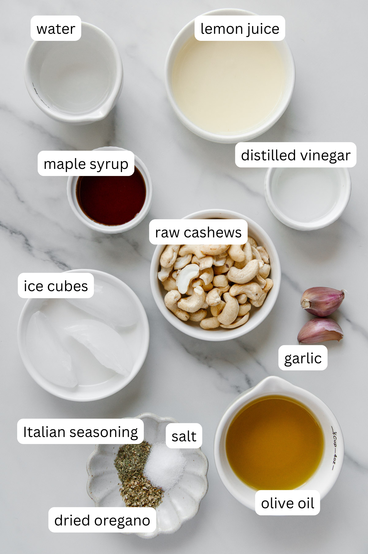 Ingredients of vegan Italian dressing with a white marble background.