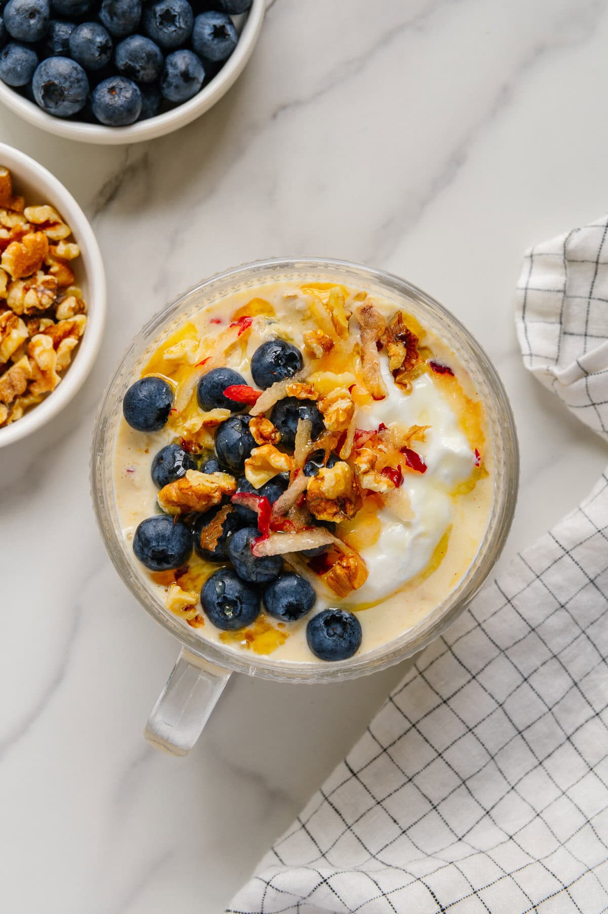 Princess Diana's overnight oats in a glass bowl with a white marble background.