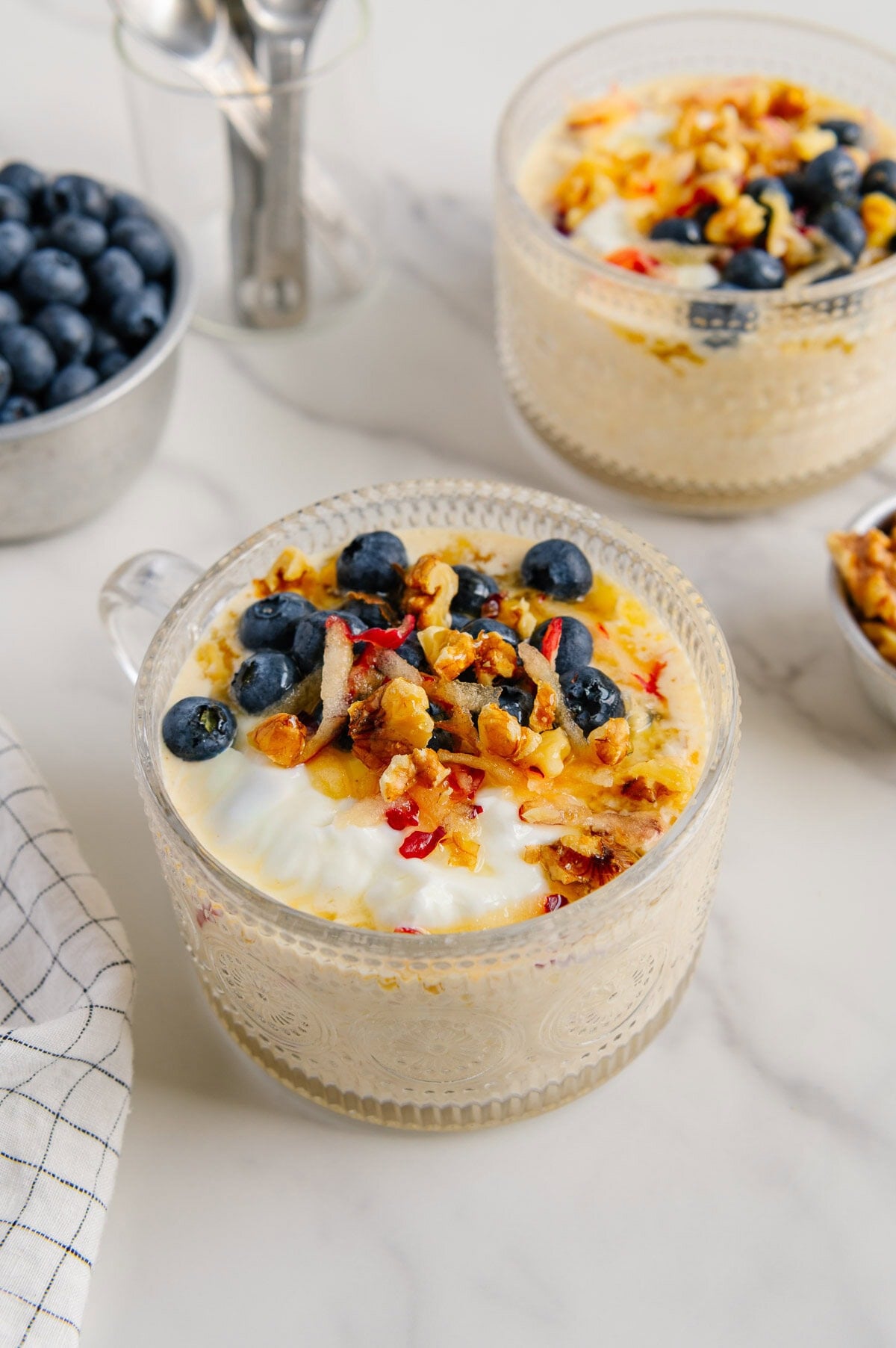 Princess Diana overnight oats in large large glass mugs with a white marble background.