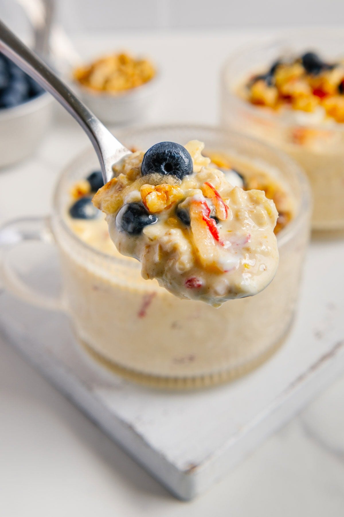 A spoonful of overnight oats with bowls of the overnight oats in the background.