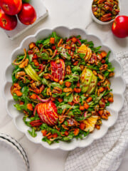 Fall harvest salad in a white bowl with a white marble background.