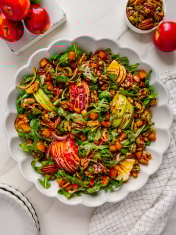 Fall harvest salad in a white bowl with a white marble background.