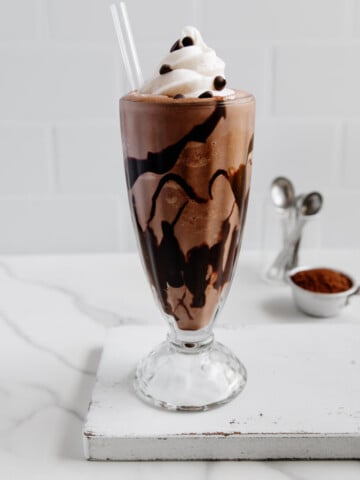 Vegan Chocolate MIlkshake Recipe in milkshake galss with whipped cream on top and chocolate chips