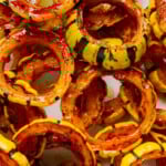 A pile of maple roasted delicata squash rings on a white plate.