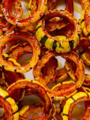 A pile of maple roasted delicata squash rings on a white plate.