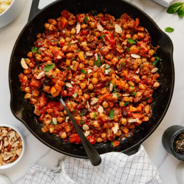 Moroccan chickpea stew in a cast iron skillet with a white background.