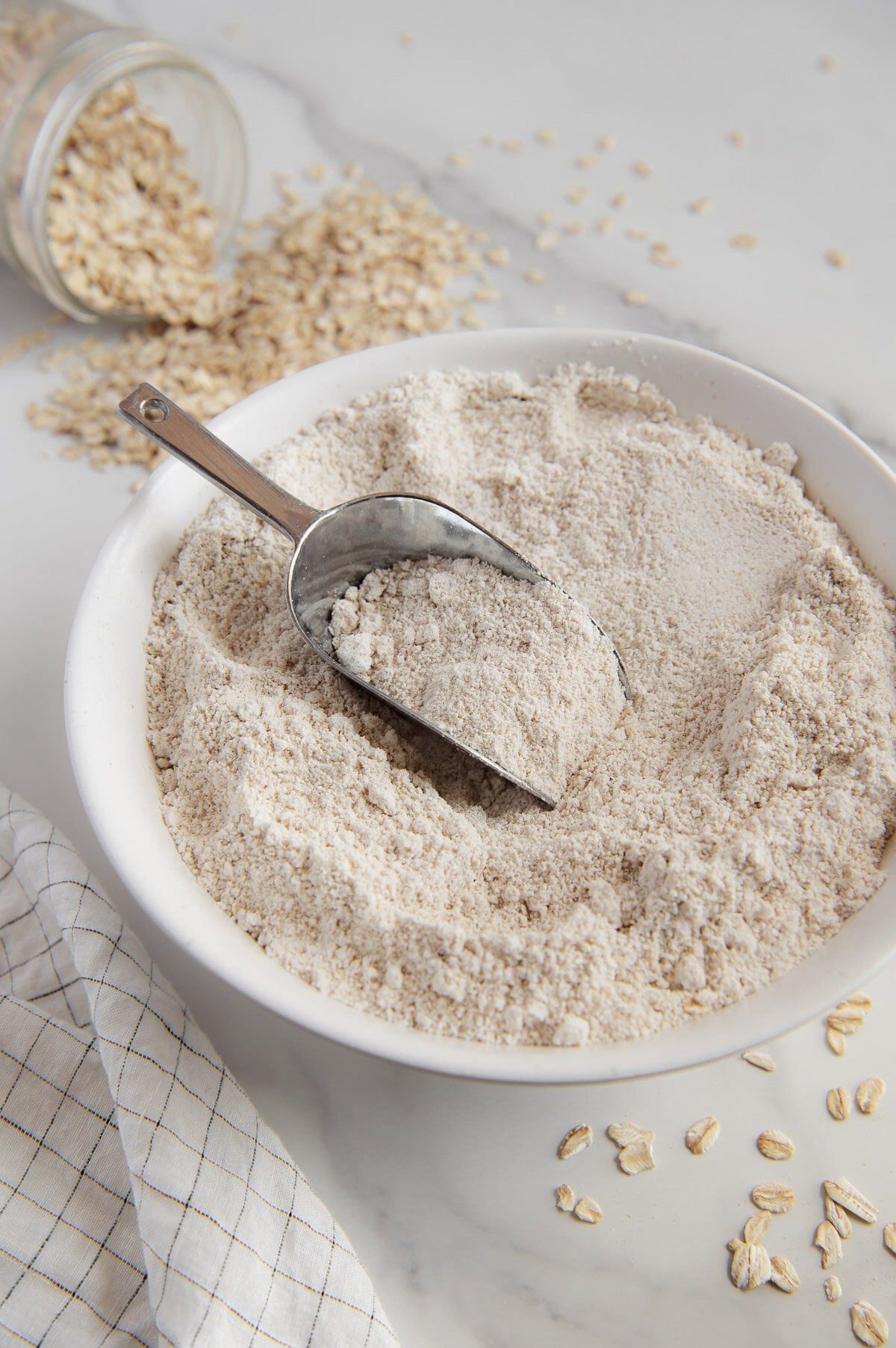 A scooper in a white bowl full of homemade oat flour.