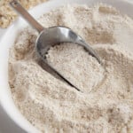 A scooper in a white bowl full of homemade oat flour.