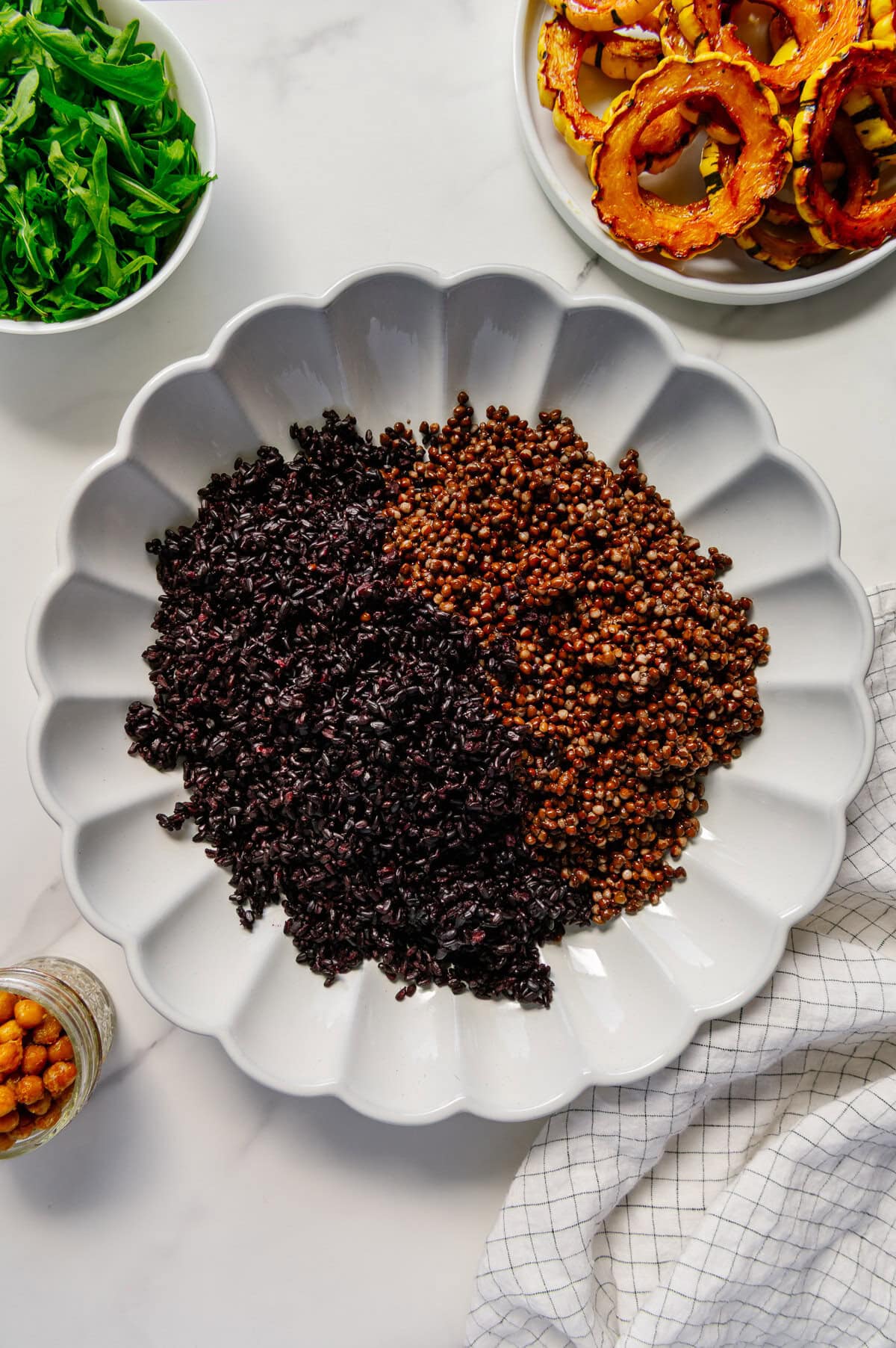 A bed of forbidden rice and cooked lentils on a large white serving plate.
