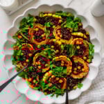 Roasted delicata squash with forbidden rice and black lentils served in a white bowl with a white marble background.
