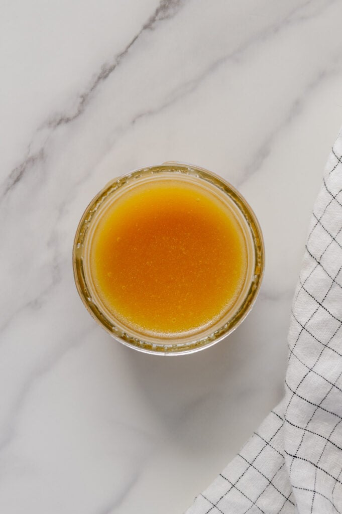 Maple lemon dressing in a small glass bowl with a white marble background.