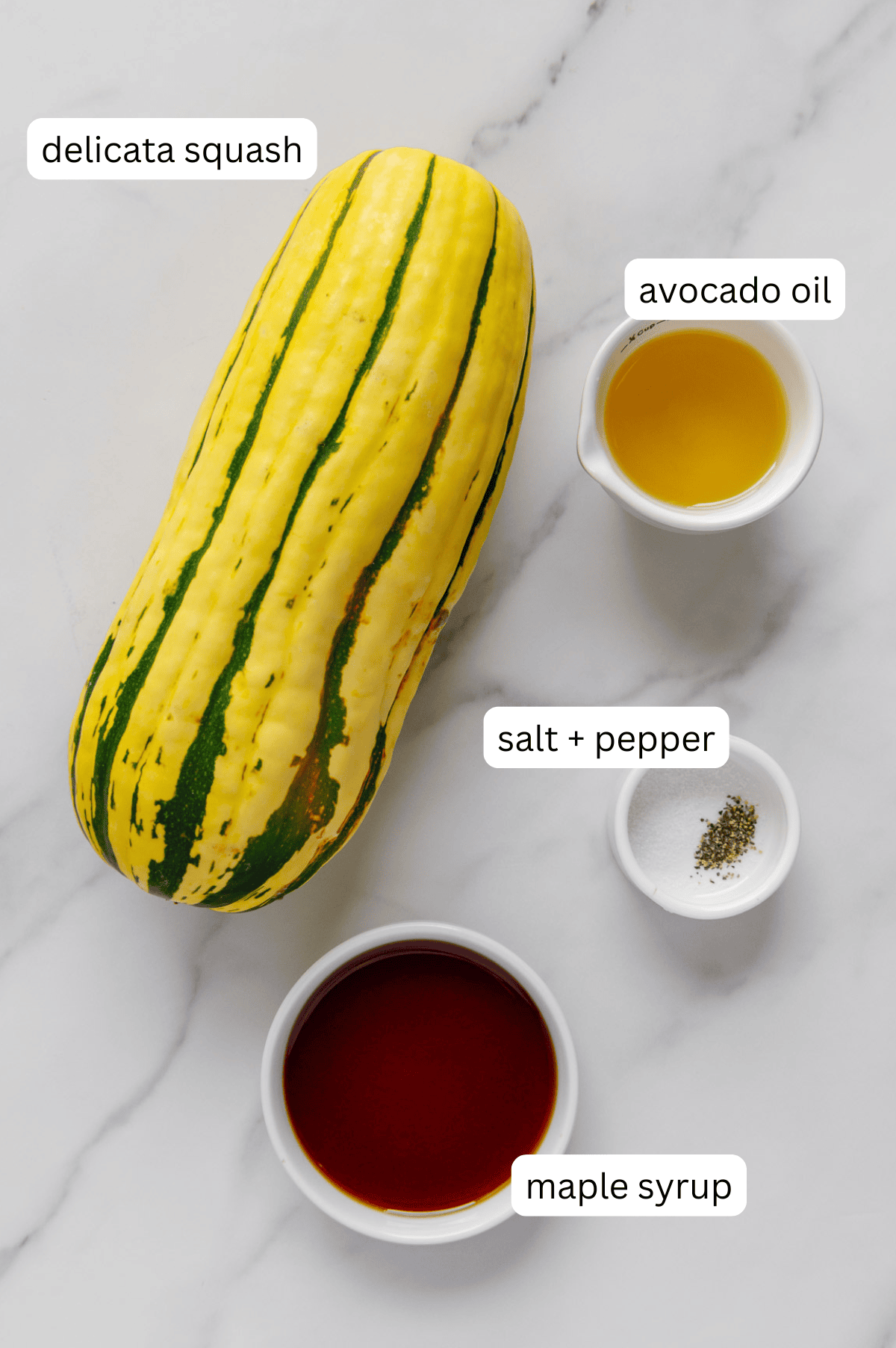 Ingredients for maple roasted delicata squash with a white marble background.