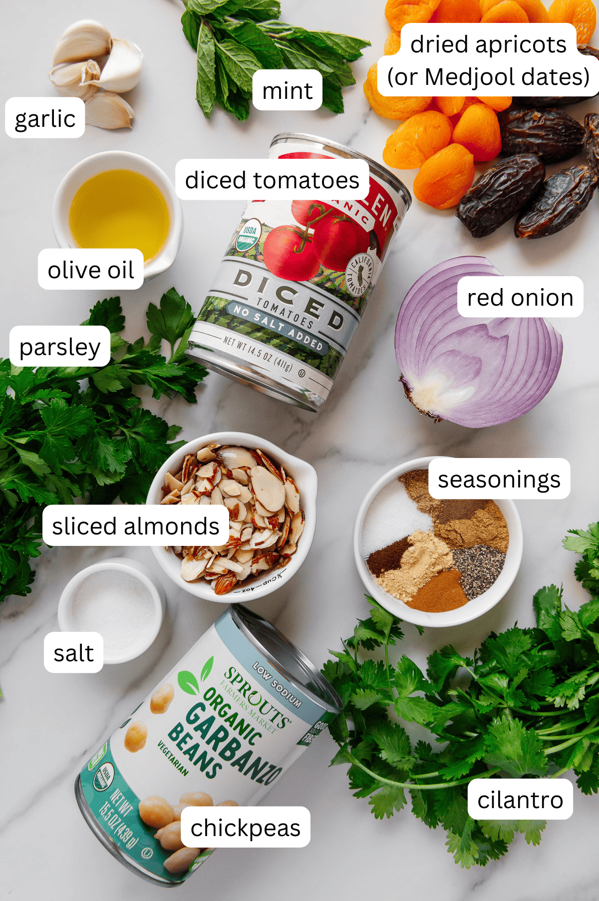Moroccan chickpeas ingredients with a white marble background.