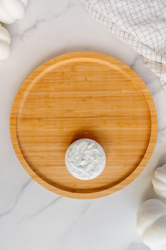 Circular wooden platter with a small bowl of vegan ranch at the bottom.