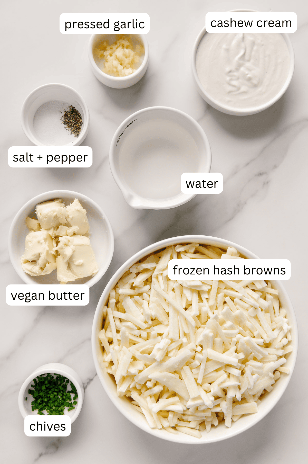 Ingredients for quick 10-minute mashed potatoes in separate bowls with a white marble background.