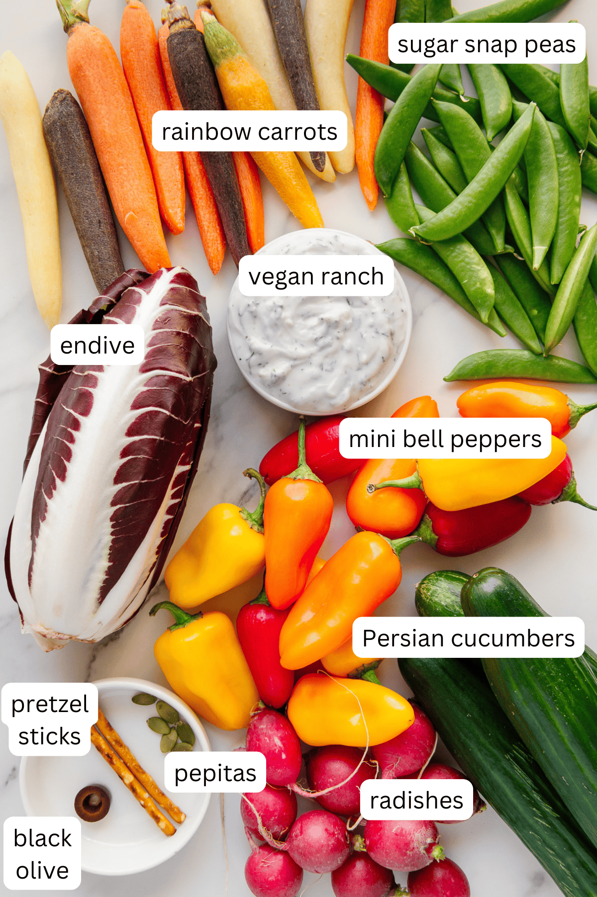 Ingredients for a Thankgiving vegetable turkey platter with a white marble background.
