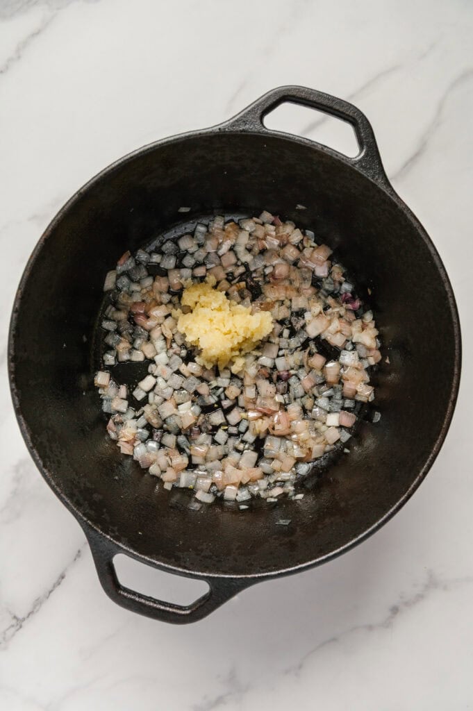 Sautéed shallots and minced garlic in a cast iron skillet.