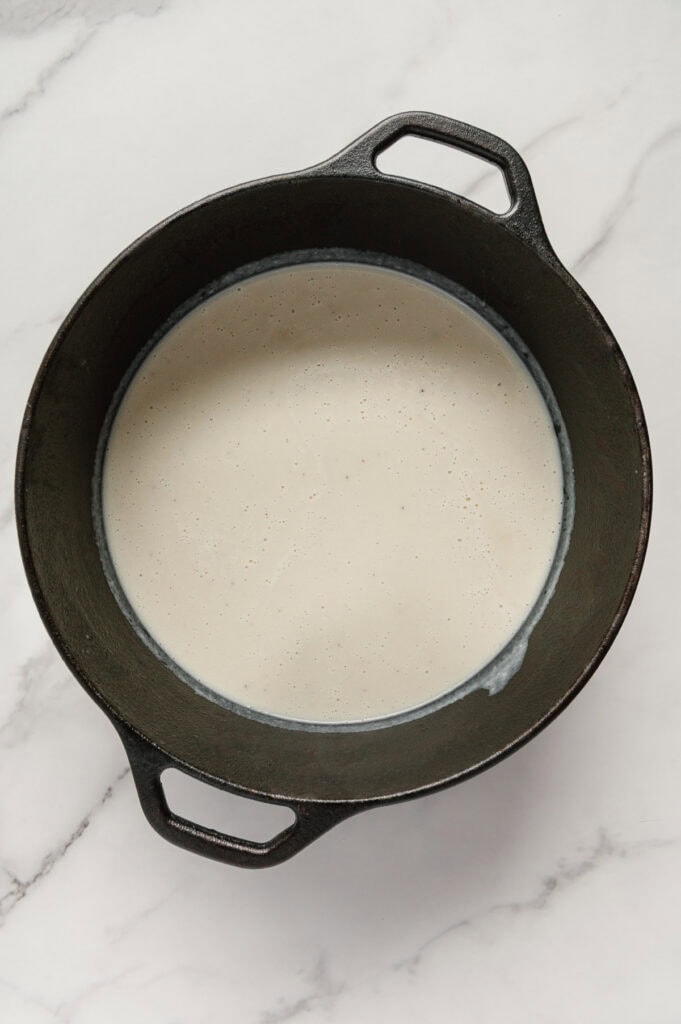 Vegan potato soup in a dutch oven with a white marble background.
