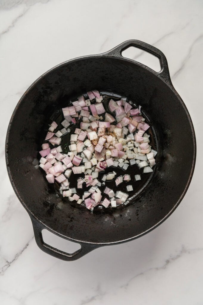 Raw shallots in a cast iron skillet.