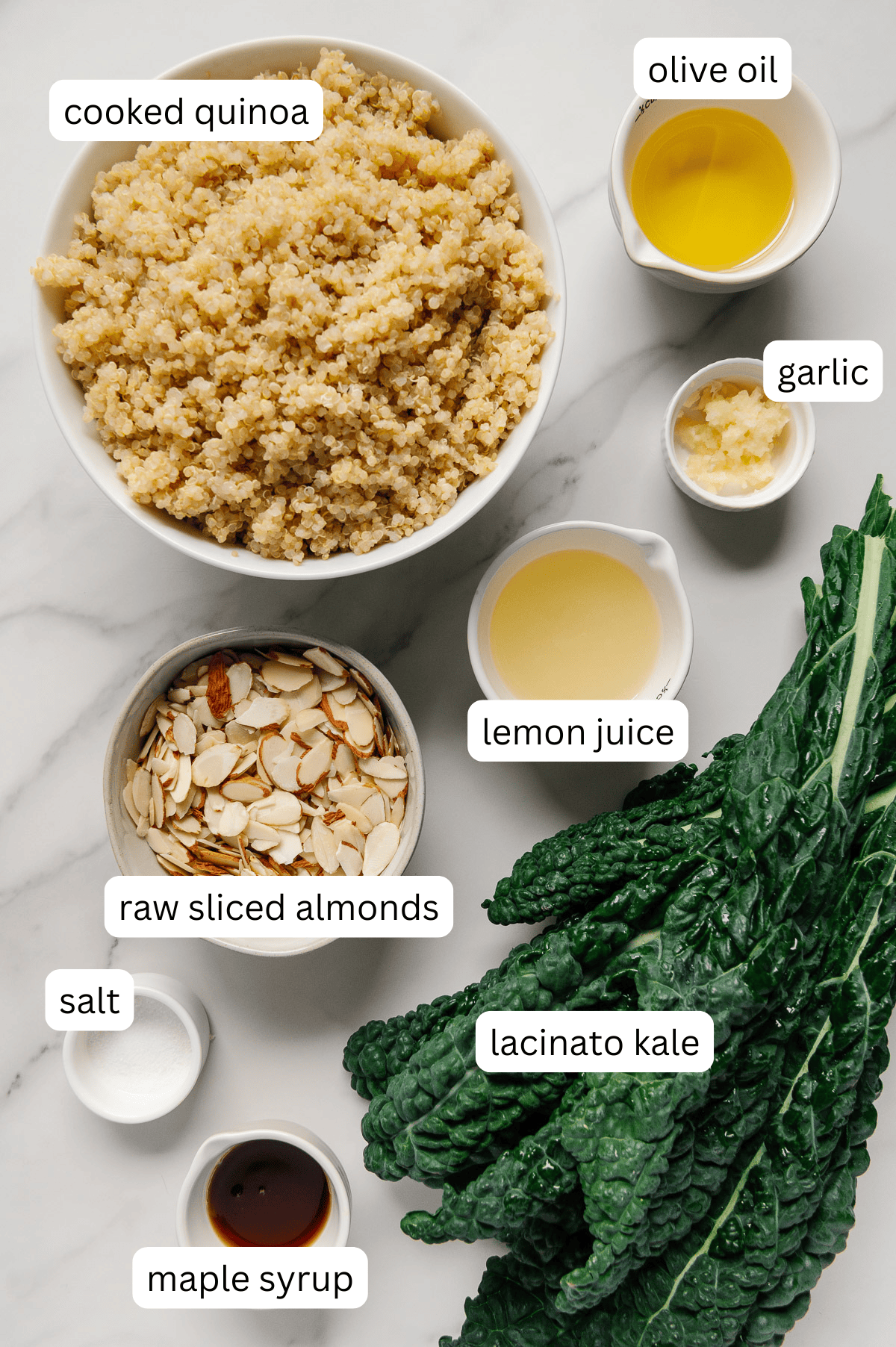 Ingredients of a kale quinoa salad with a white marble background.