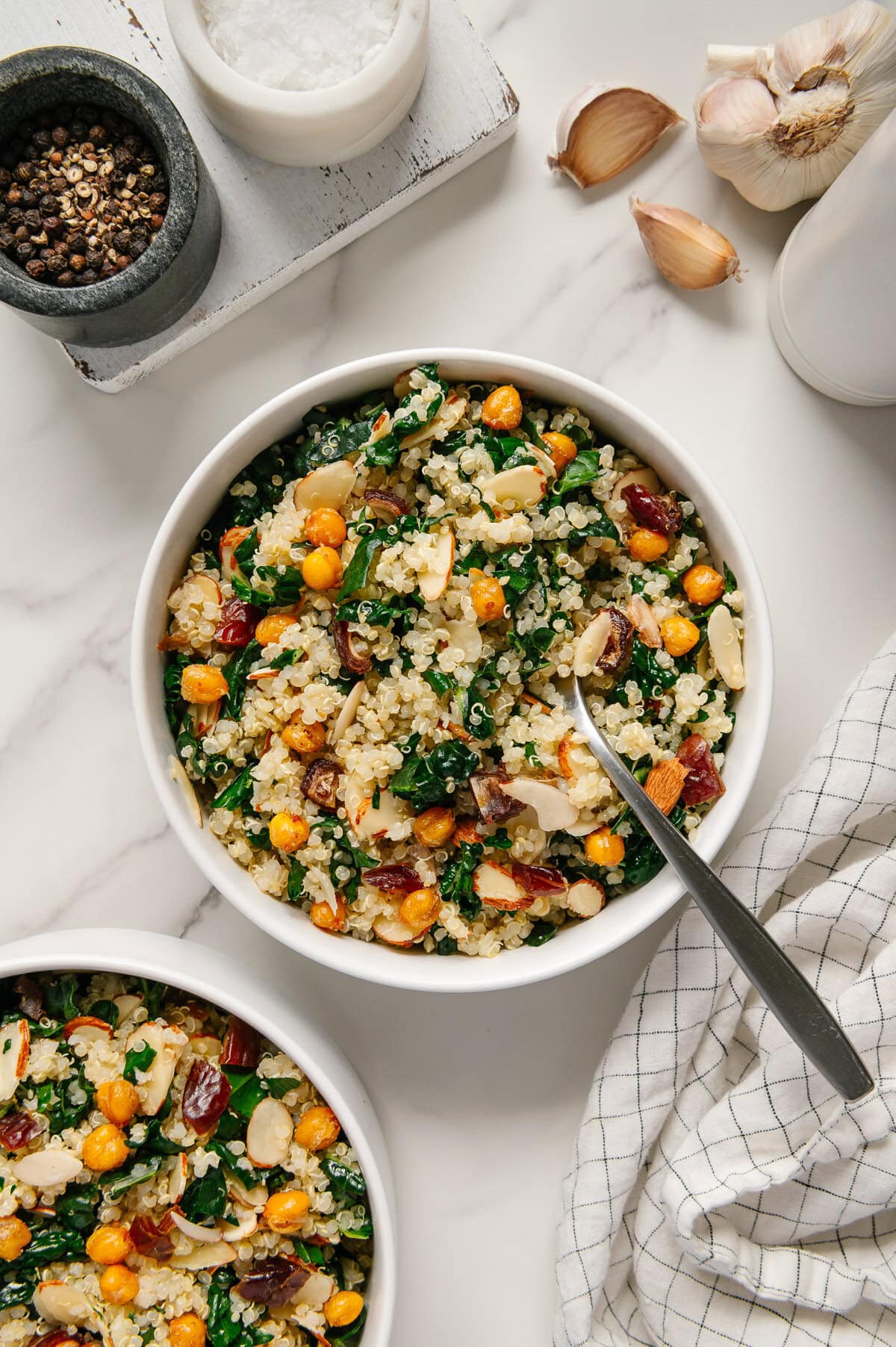 Kale quinoa salad in a small white bowl topped with crispy chickpeas.
