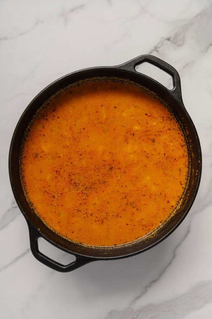 Vegan cabbage soup in a dutch oven with a white marble background.