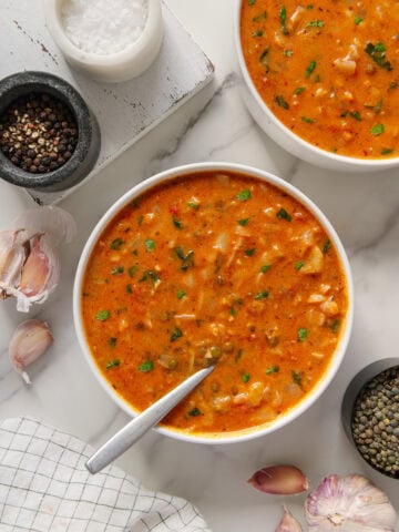 Vegan cabbage soup served in two white bowls with a white marble background.