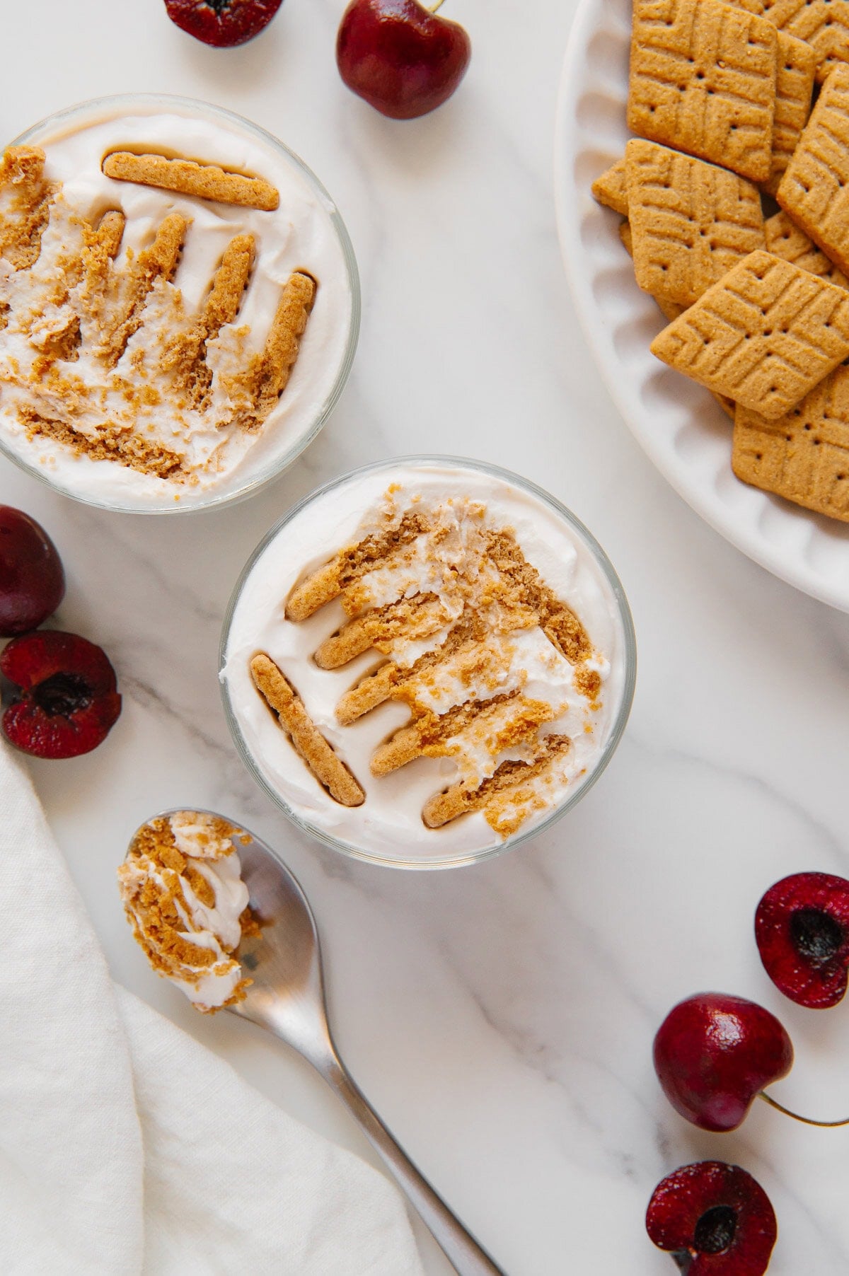 Viral 2-ingredient Japanese cheesecake in two small glasses next to a plate of Simple Mills cookies with a white marble background.