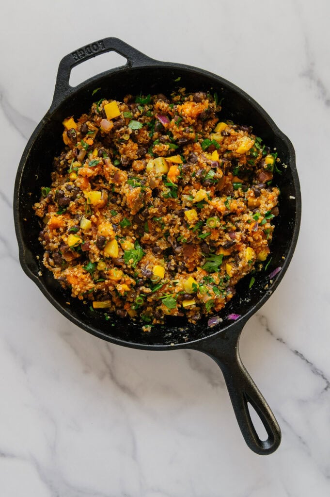 Enchilada stuffing mixture in a cast iron skillet with fresh cilantro and green onions mixed in.