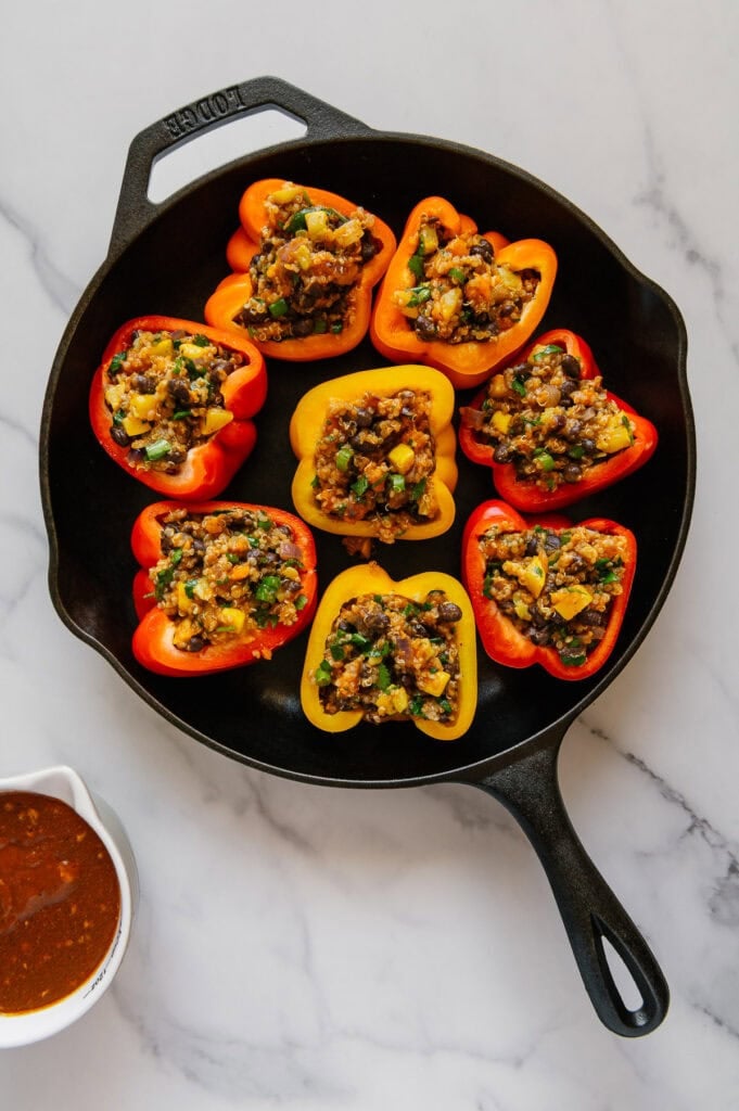 Enchilada stuffed bell peppers in a cast iron skillet prior to being roasted.