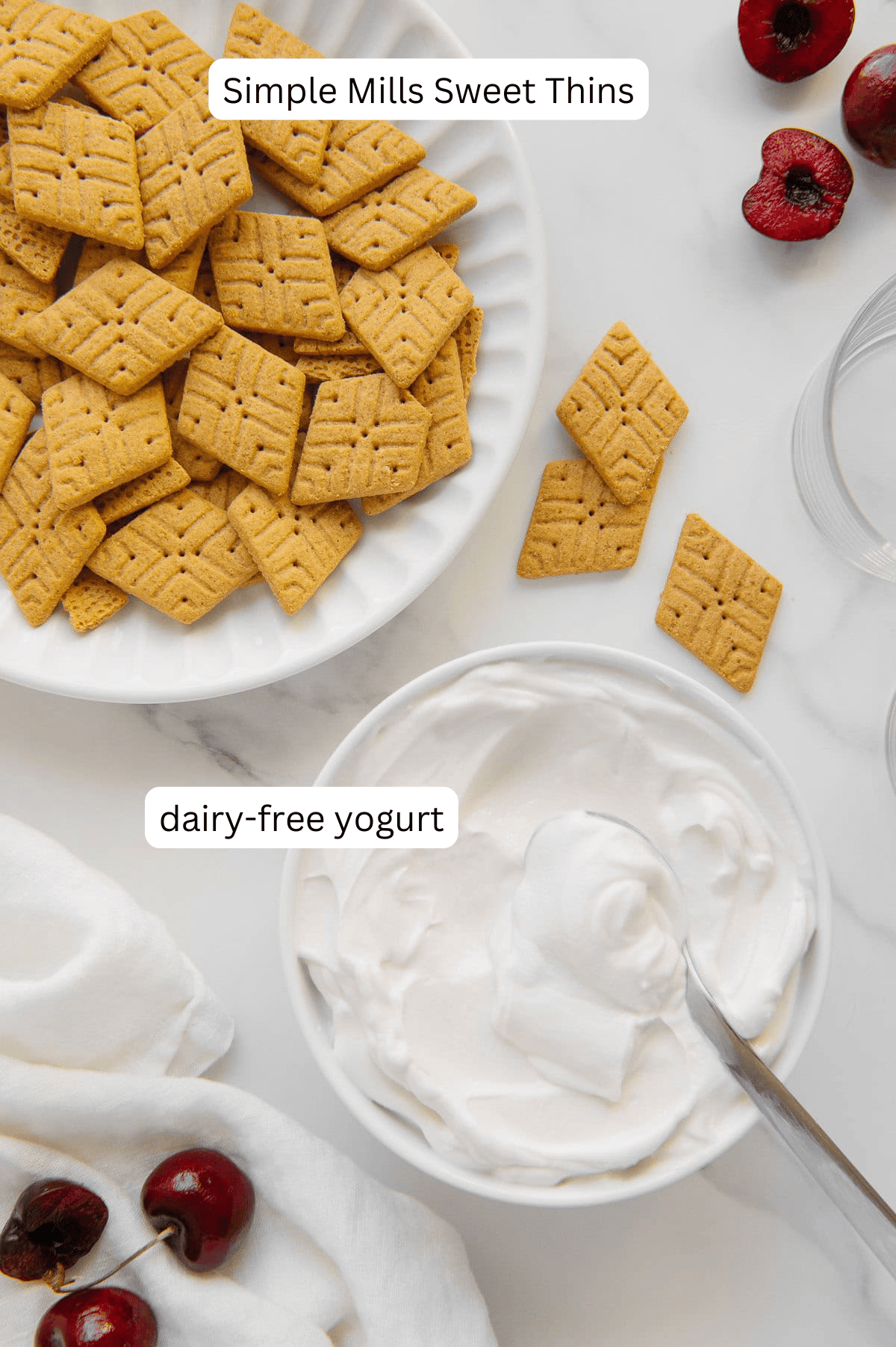 A plate of Simple Mills Sweet Thins and a bowl of dairy-free yogurt next to each other with a white marble background.