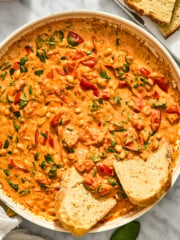 A skillet of creamy Tuscan white bean stew garnished with fresh basil, served with slices of crusty bread.