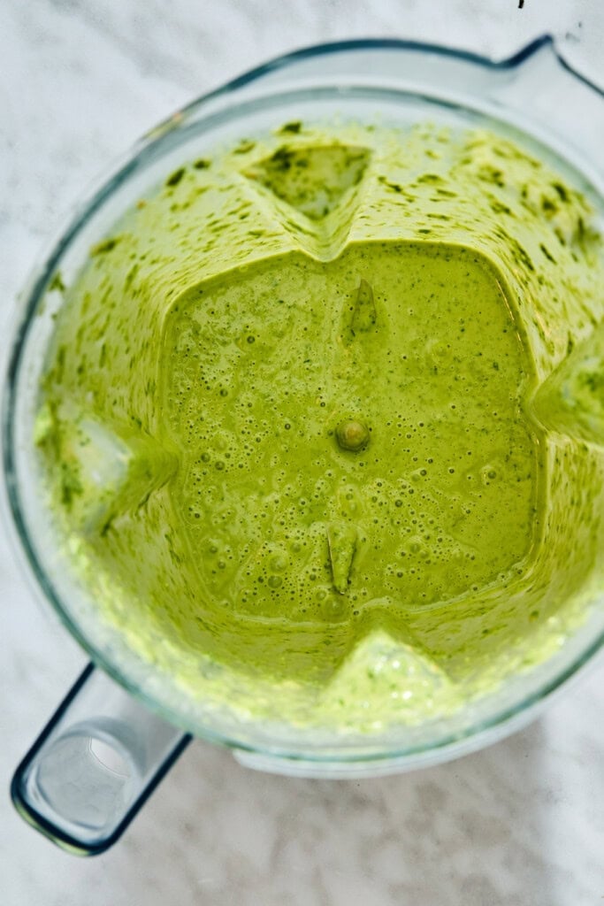 A vibrant green blended sauce in a glass blender pitcher, perfect for a high-protein chickpea salad.