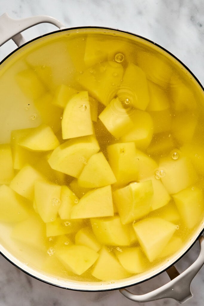 Chunks of chopped potato submerged in water inside a large pot.