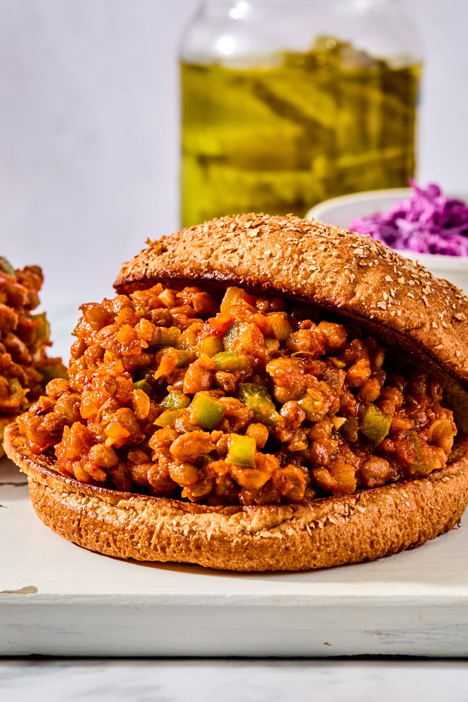 A sloppy joe sandwich with a savory meat and vegetable filling on a sesame seed bun.